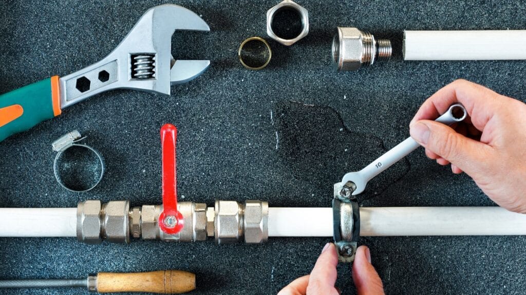 Plumber repairing a pipe valve with an adjustable wrench in Jurupa Valley