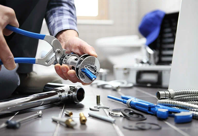 Technician repairing a plumbing fixture with professional tools in Jurupa Valley