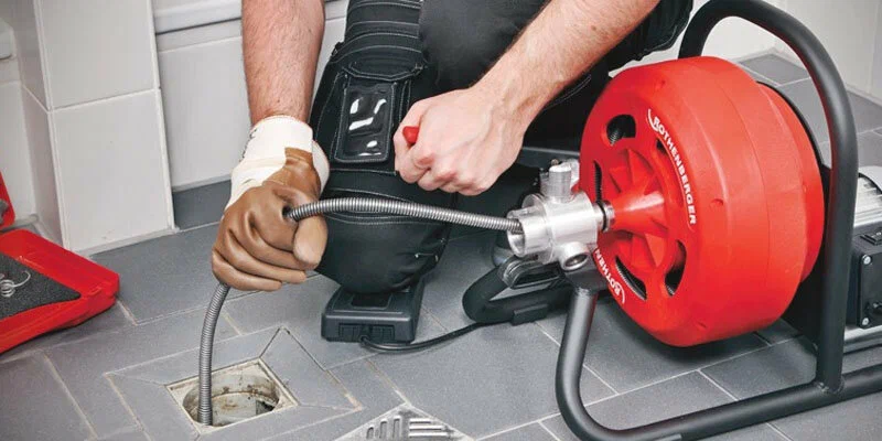Plumber using a drain-cleaning machine in Jurupa Valley