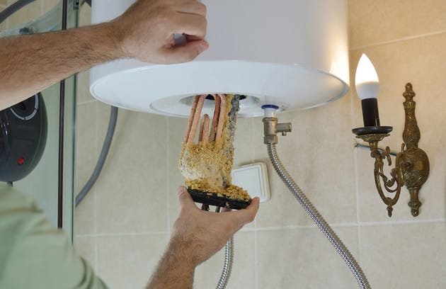 Technician removing mineral buildup from a water heater in Jurupa Valley