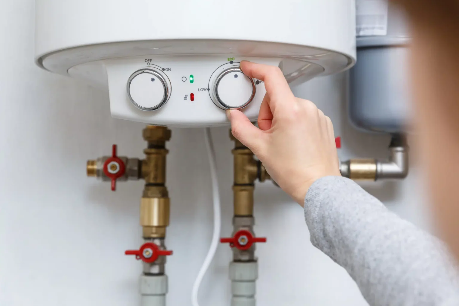 Homeowner adjusting the temperature controls on a water heater in Jurupa Valley